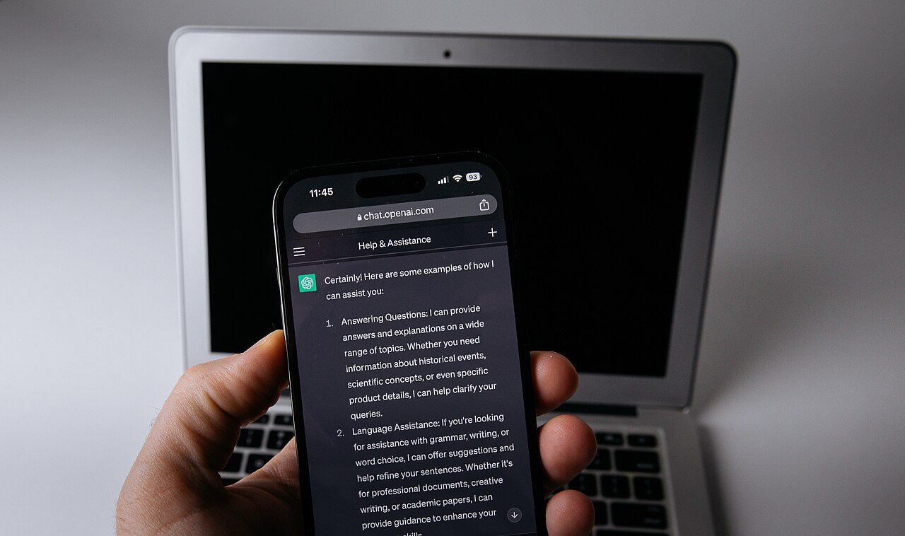 Celular com o ChatGPT aberto no navegador ao lado de um notebook