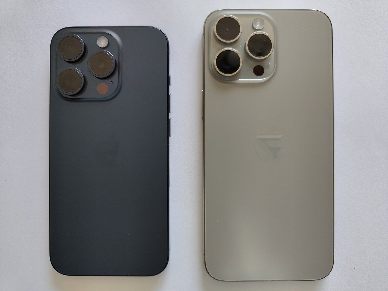 iPhone 15 Pro e iPhone 15 Pro Max vistos de trás, um titânio azul e outro titânio natural