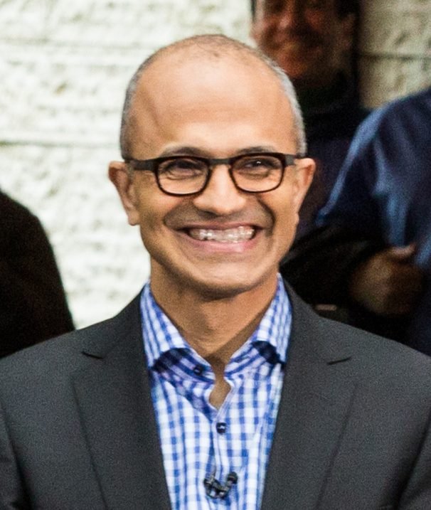 Satya Nadella, CEO da Microsoft, sorrindo, de óculos e blazer escuro