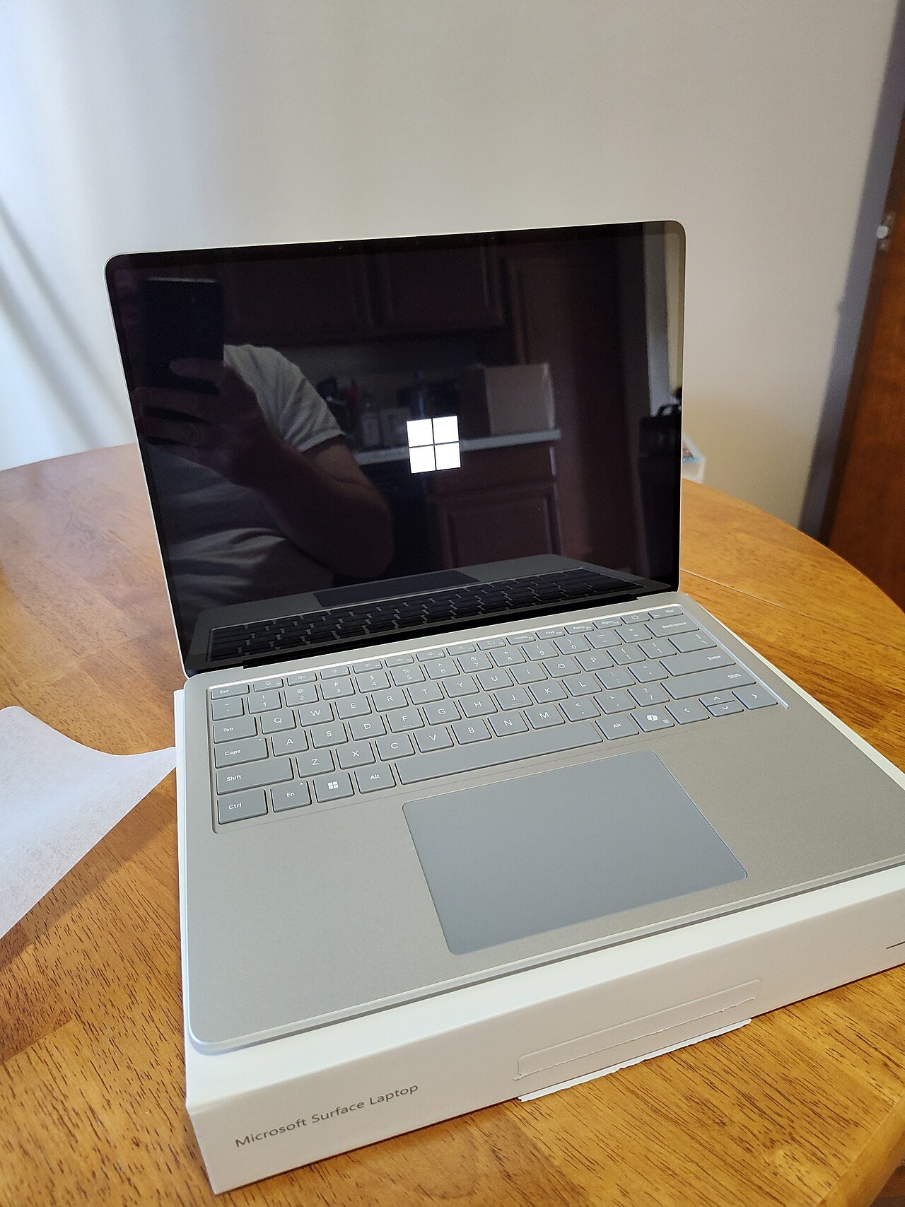 Notebook Microsoft Surface Laptop aberto sobre a caixa, mostrando o logotipo do Windows na tela